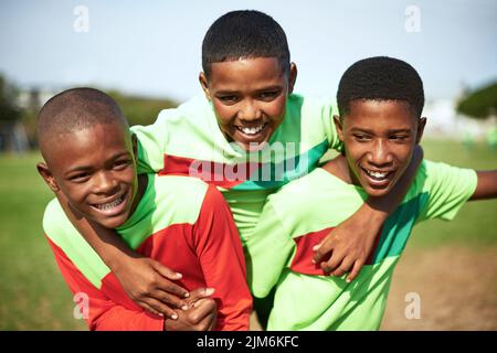 Nous sommes devenus les meilleurs amis après une rencontre sur le terrain. Un groupe de jeunes garçons jouant au football sur un terrain de sport. Banque D'Images