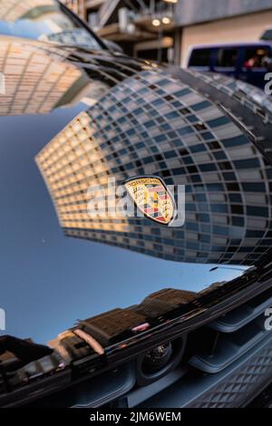 Le tout nouveau logo Porsche Cayenne 2022 sur la vitre de la voiture sur un arrière-plan de bâtiment flou Banque D'Images