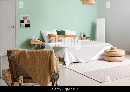 Intérieur d'une chambre confortable avec poufs en rotin, miroir et fauteuil Banque D'Images