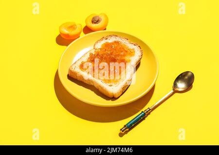 Assiette de délicieux toasts à la confiture d'abricot sur fond jaune Banque D'Images