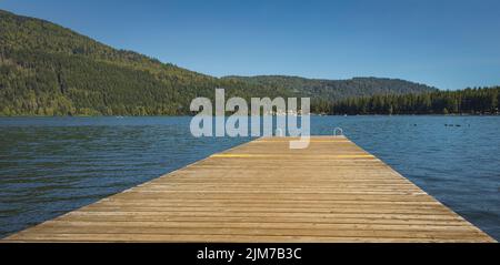 Jetée en bois avec échelle en métal dans la mer, le lac, l'eau. Quai de baignade avec échelle en métal sur le lac bleu calme à la journée ensoleillée sur la station idyllique au culte Banque D'Images