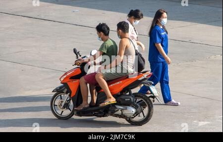 SAMUT PRAKAN, THAÏLANDE, APR 15 2022, Un deux homme roule sur une moto à côté des femmes marchant. Banque D'Images