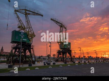 Des grues historiques sur les boulevards au bord de la rivière à Szczecin pendant un lever de soleil spectaculaire Banque D'Images