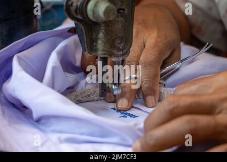 Broder des numéros thaïlandais sur une chemise d'étudiant sur une vieille machine à coudre Banque D'Images