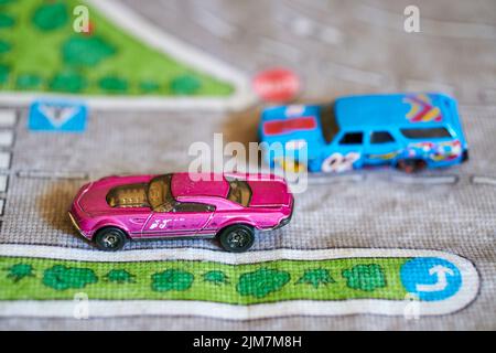 Un foyer sélectif d'un mélange de voitures de jouet Mattel Hot Wheels modèle rose et bleu sur un tapis de route de jeu Banque D'Images