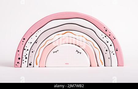 Jouet arc-en-ciel en bois d'arcs. Concept de sommeil des enfants. Joli jeu pour tout-petit dans des couleurs pastel rose tendre. Développement de la coordination main-œil Banque D'Images