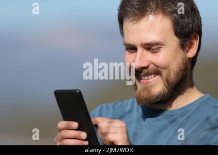 Gros plan d'un homme heureux utilisant un téléphone portable un jour ensoleillé Banque D'Images