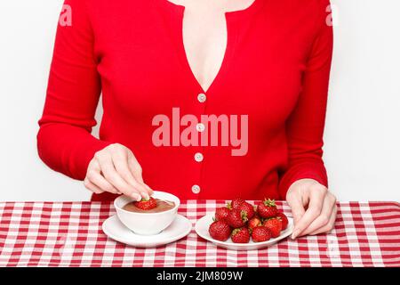 Femme mangeant de fondue au chocolat et aux fraises, fête Banque D'Images