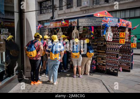 Un groupe de touristes portant des chapeaux jaunes identiques se trouve dans un kiosque souvenir touristique de Regent Street, dans le West End, le 3rd août 2022, à Londres, en Angleterre. Banque D'Images