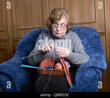 La vieille femme est assise dans un fauteuil Banque D'Images