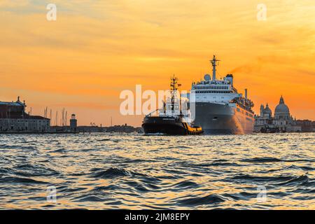 VENISE, ITALIE - 9 SEPTEMBRE 2018 : ce bateau de croisière quitte la ville avec un remorqueur au coucher du soleil. Banque D'Images