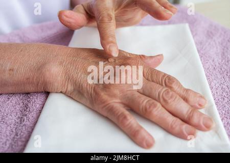 gros plan, les mains de la vieille femme. grand-mère frotte une pommade réchauffante pour l'arthrite Banque D'Images