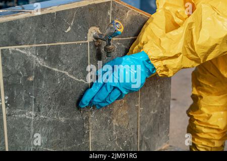 Prise d'un gant de protection lors du lavage à la fontaine avec mise au point sélective. Banque D'Images