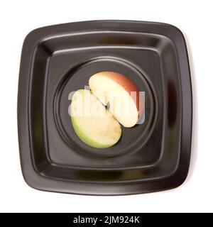 Les deux moitiés d'une pomme sur une assiette Banque D'Images