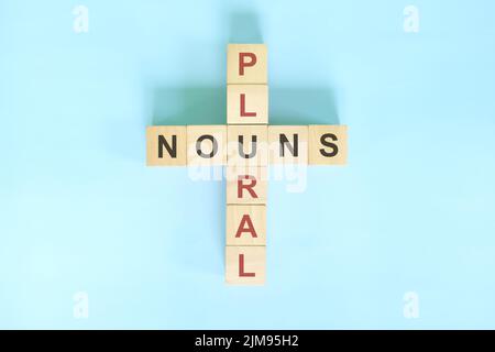 Concept de noms pluriel dans l'enseignement de la grammaire anglaise. Jeu de mots croisés en bois posé sur fond bleu. Banque D'Images