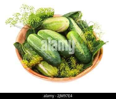 Les concombres et les feuilles d'aneth restent en vie dans un bol en bois isolé sur fond blanc. Banque D'Images