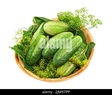 Les concombres et les feuilles d'aneth restent en vie dans un bol en bois isolé sur fond blanc. Banque D'Images