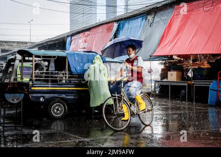 Bangkok, Thaïlande. 05th août 2022. Un vendeur sur une bicyclette avec un parapluie traverse les inondations lors de fortes pluies sur le marché humide de Khlong Toey à Bangkok. La vie quotidienne autour du marché de Khlong Toey Wet à Bangkok. Alors que le tourisme continue de croître avec l'arrivée de 3 millions de touristes internationaux cette année, le taux d'inflation de détail de la Thaïlande a augmenté de 7,66% depuis un an, ce qui l'a porté à un niveau élevé de 14 ans et a conduit à des spéculations selon lesquelles la banque centrale augmentera le taux d'intérêt en août 2022. Crédit : SOPA Images Limited/Alamy Live News Banque D'Images