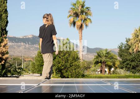 Vue de face d'une jeune femme qui se tient à l'arrière-plan avec de la végétation et des panneaux solaires sur le côté Banque D'Images