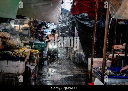 Bangkok, Thaïlande. 05th août 2022. Un motocycliste traverse une allée inondée lors de fortes pluies au marché humide de Khlong Toey à Bangkok. La vie quotidienne autour du marché de Khlong Toey Wet à Bangkok. Alors que le tourisme continue de croître avec l'arrivée de 3 millions de touristes internationaux cette année, le taux d'inflation de détail de la Thaïlande a augmenté de 7,66% depuis un an, ce qui l'a porté à un niveau élevé de 14 ans et a conduit à des spéculations selon lesquelles la banque centrale augmentera le taux d'intérêt en août 2022. Crédit : SOPA Images Limited/Alamy Live News Banque D'Images