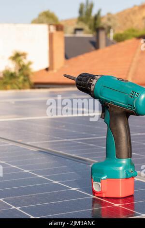 Vue verticale rapprochée d'un tournevis électrique bleu et rouge sur une centrale solaire sous le soleil Banque D'Images