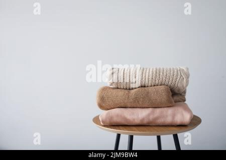 Pile de vêtements pour femmes propres fraîchement lavés et soigneusement pliés sur une table en bois. Chandails chauds d'automne. Banque D'Images
