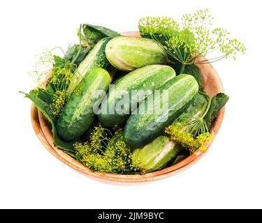 Les concombres et les feuilles d'aneth restent en vie dans un bol en bois isolé sur fond blanc. Banque D'Images