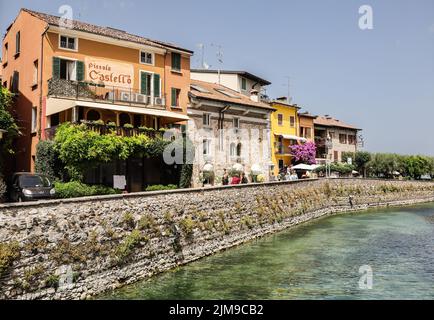 Sirmione, Italie - 25 juin 2022: Ville pittoresque de Sirmione avec des maisons colorées dans le nord de l'Italie. Belle architecture de la ville avec le canal de l'eau. Banque D'Images