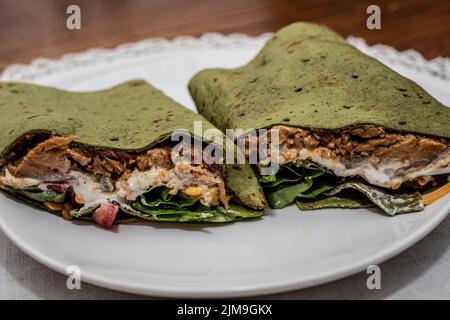 Rôti de porc au piment vert mijoté dans du pain plat aux épinards avec du fromage cheddar râpé, de la tomate, des épinards et de la crème aigre. Banque D'Images