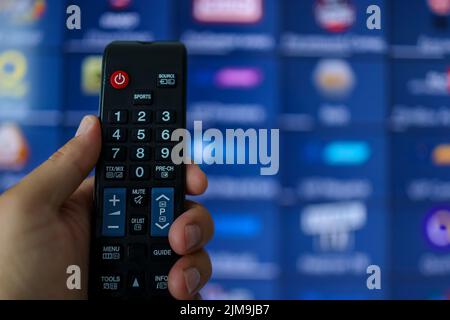 Smart tv et télécommande. Main tenant la télécommande du téléviseur avec un téléviseur en arrière-plan. Gros plan. Banque D'Images