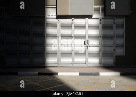 Un fragment de lumière du soleil touche des portes à persiennes en aluminium gris à l'extérieur d'un bâtiment urbain à Dubaï, aux Émirats arabes Unis. Banque D'Images