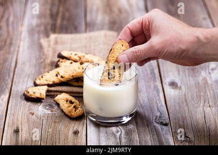 Trempez à la main des biscuits aux pépites de chocolat faits maison dans un verre de lait Banque D'Images