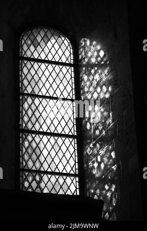 Image verticale en niveaux de gris d'une fenêtre et reflet de la lumière sur le mur Banque D'Images