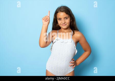 Brunette hispanique fille en maillot de bain montrant et pointant vers le haut avec le doigt numéro un tout en souriant confiant et heureux. Banque D'Images