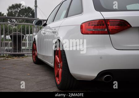 Une Audi A4 avant blanche aux jantes rouge vif garée sur les rives du Rhin à Düsseldorf, en Allemagne. Banque D'Images