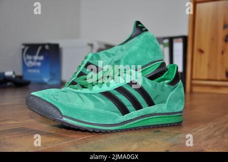 Un gros plan des sneakers vertes Adidas rétro pour coureurs. Banque D'Images