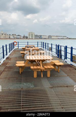 Places et tables désertes sur la jetée d'Eastbourne, Royaume-Uni Banque D'Images