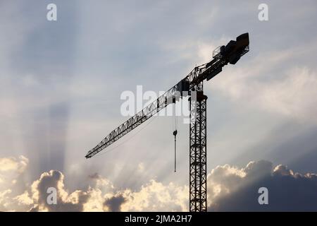 Silhouette de la tour de grue sur le ciel du coucher du soleil avec des nuages et des poutres de soleil arrière-plan Banque D'Images