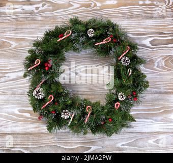 Couronne de Noël avec des lumières et des cannes de bonbons sur des planches de bois blanches Banque D'Images