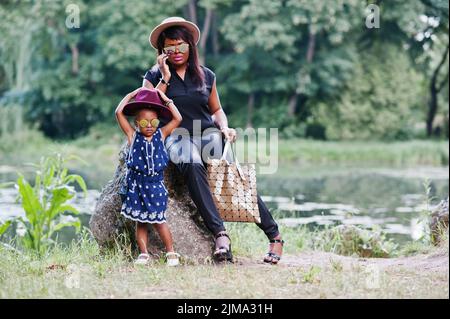 African American Style mère et fille à lunettes de soleil. Black woman with mobile phone Banque D'Images