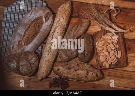 différents types de pains artisanaux à levain décorés d'épis de blé sur une table en bois Banque D'Images