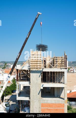 une grue automotrice extra-robuste décharge les matériaux en fer dans un bâtiment érigé Banque D'Images