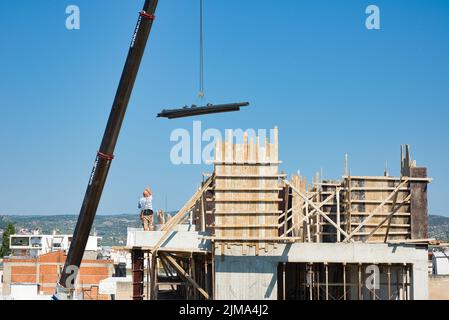 une grue automotrice extra-robuste décharge les matériaux en fer dans un bâtiment érigé Banque D'Images