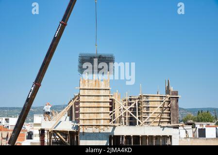 une grue automotrice extra-robuste décharge les matériaux en fer dans un bâtiment érigé Banque D'Images