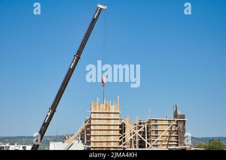 une grue automotrice extra-robuste décharge les matériaux en fer dans un bâtiment érigé Banque D'Images
