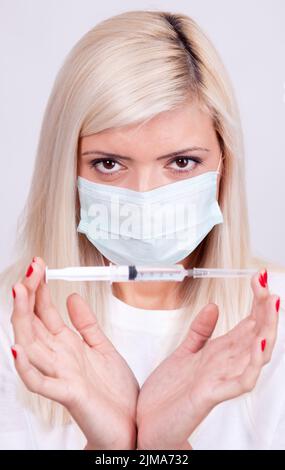 Femme médecin ou infirmière dans un masque médical tenant une seringue avec injection, vaccin contre le virus corona Banque D'Images