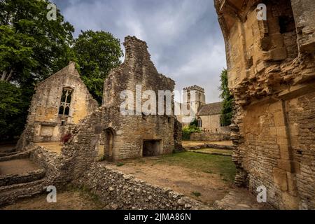 Les ruines atmosphériques de Minster Lovell Hall avec l'église St Kenelm en arrière-plan, Cotswolds, Oxfordshire, Angleterre Banque D'Images