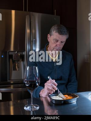 Homme solitaire senior mangeant un repas prêt à table Banque D'Images