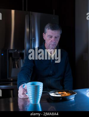 Homme solitaire senior mangeant un repas prêt à table Banque D'Images