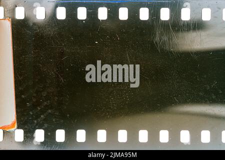 Texture ou surface poussiéreuse et rugueuse du film 35 mm.Film perforé rayé isolé sur fond blanc. Banque D'Images